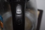 Верхняя кнопка открывает крышку, нижняя - включает и выключает чайник