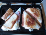 Слева - яичница с кусочками колбасы и хлеба. Справа - квадратные тосты, которые тостер разрезал на 2 части.