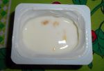 Открытая баночка с йогуртом, где видны кусочки персика